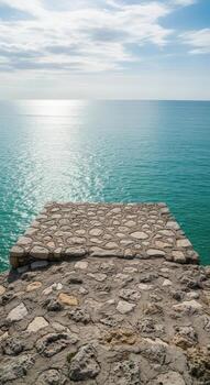 vertical ver de un Roca plataforma por el iluminado por el sol Oceano foto