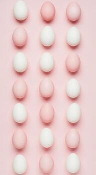 Rows of pink and white easter eggs arranged on a pink background photo
