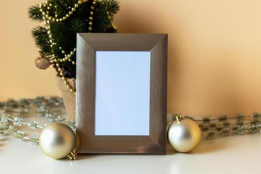 Mockup. Christmas. Elegant empty photo frame placed on table, surrounded by golden ornaments and small Christmas tree, creating warm and festive atmosphere perfect for holiday memories