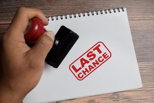 Red Handle Rubber Stamper and Last chance text above book isolated on wooden background photo