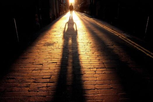 A person walking down a street with the sun setting behind them photo