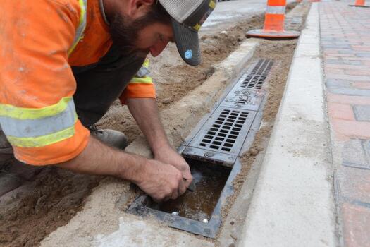 A man is fixing a drain in the street photo