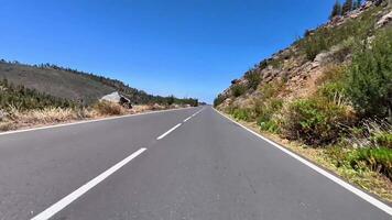A stunningly beautiful mountain road, enveloped by lush greenery and expansive clear blue skies above it video