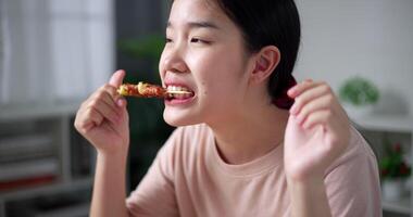 contento asiatico donna godendo delizioso barbecue nel vivente camera a casa. fatti in casa cibo. mangiare con rilassamento video