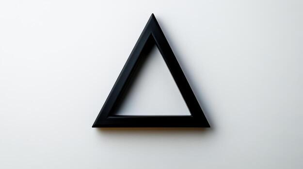 A black triangle shaped object on a white wall photo