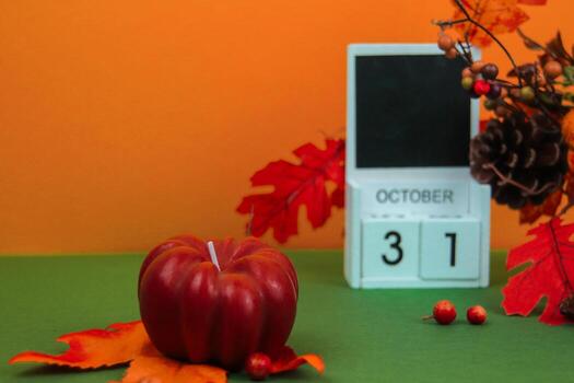 A pumpkin-shaped candle stands in the foreground, with a calendar with the Halloween date in the background photo
