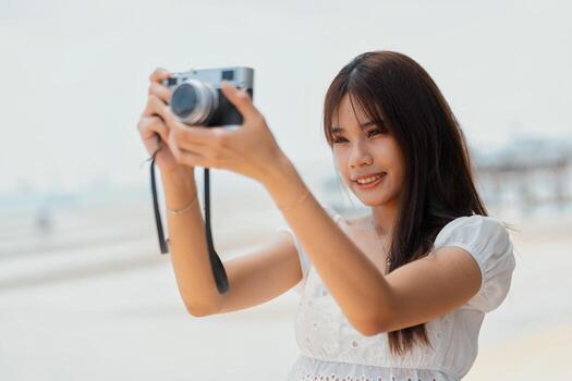 Woman capturing memories at the beach while enjoying a sunny day with a camera in hand photo