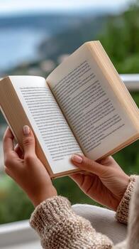 Woman reading book on balcony with view of mountains photo