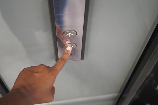 Hand pressing elevator button to go up in modern building photo