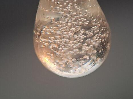 An abstract composition of trapped air bubbles within a clear, teardrop shaped form with light play. photo