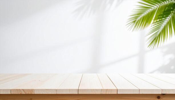 Wooden table top with palm tree in front of white wall photo