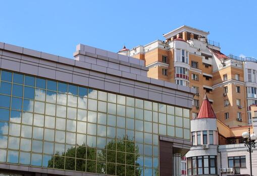 Mirror Facade Of Office Building With Reflection Of Trees And Clouds In Front Of Variety Apartment Houses photo