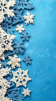 Crocheted white and blue snowflakes on a vibrant blue textured background, arranged along the left side, leaving ample copy space on the right photo