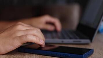 händer göra flera saker samtidigt mellan bärbar dator och smartphone, närbild, göra flera saker samtidigt påfrestning, begrepp av modern arbete, avlägsen jobb, digital livsstil, kommunikation, och produktivitet i teknikdrivet miljö video