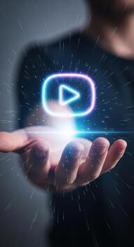 Glowing play button icon held in a hand, digital media concept photo