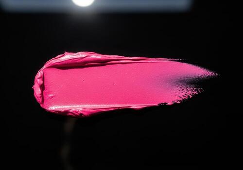 Pink lipstick swatch with shimmer on black background photo
