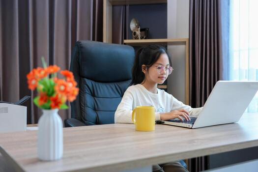 Young schoolgirl doing her class homework assignment at home using laptop computer for education and study concept photo