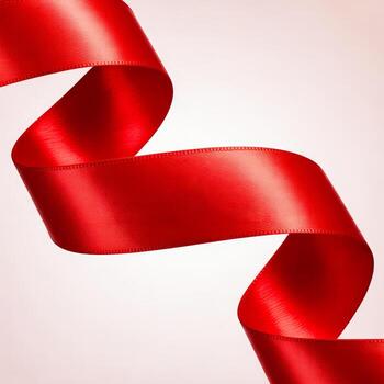 Shiny red ribbon elegantly curled against a soft background photo