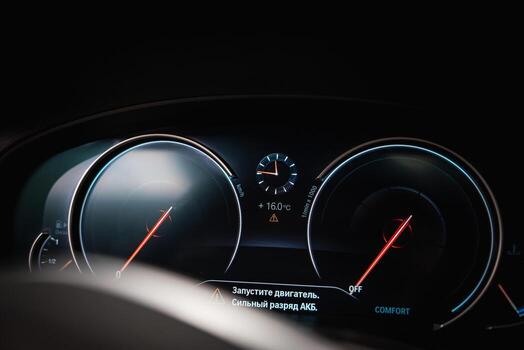 Close up of a BMW dashboard showing speedometer, tachometer, and digital display in Russian with engine start message and battery warning. photo