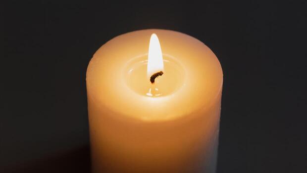 Flickering Flame Illuminates White Candle in a Darkened Room Creating a Serene Atmosphere photo