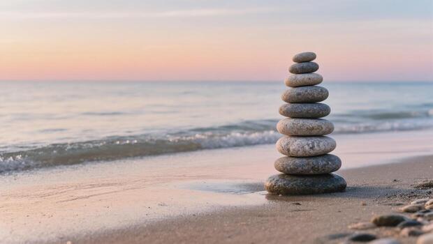 Balanced Stone Tower Rests on Sandy Beach During Serene Twilight by the Calm Ocean photo