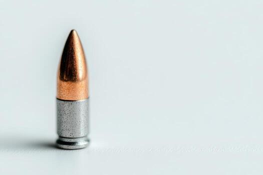 Single bullet isolated on a white surface during daylight hours photo