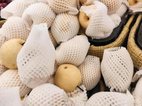 Top angle shot of yellow pears wrapped with Polyethylene foam in grocery store. A pile of pears covered by a fruit net to protect them from bumps and scratches. Graphic Resources. Copy space photo