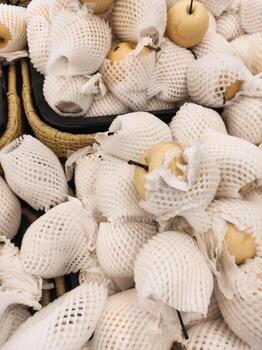 Top angle shot of yellow pears wrapped with Polyethylene foam in grocery store. A pile of pears covered by a fruit net to protect them from bumps and scratches. Graphic Resources. Negative space photo