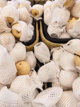 Top angle shot of yellow pears wrapped with Polyethylene foam in grocery store. A pile of pears covered by a fruit net to protect them from bumps and scratches. Graphic Resources. Text space photo