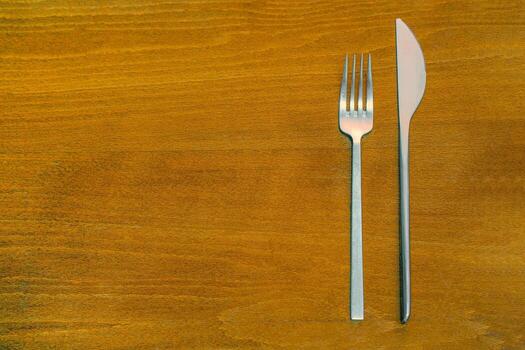 Knife and fork on a wooden table. Fork and knife on the dark old wood background. Top View with Text Space. photo