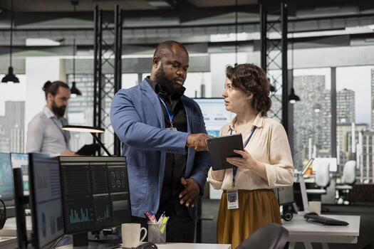 Diverse group of employees collaborate on project planning and analysis, using data from charts on tablet to drive performance metrics. Fostering teamwork and a workplace alliance. photo