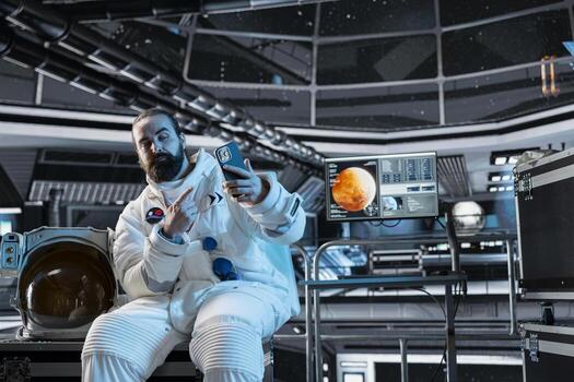 Astronaut on orbital station talking selfies with smartphone while flying to Mars. Astronaut in spaceship taking pictures with mobile phone during red planet surface research expedition photo