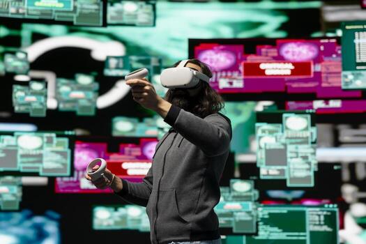 Man uses virtual reality headset for system corruption and password cracking, cyber intelligence define this tech driven information theft. Intrusion and threat alerts reveal dangerous hacking. photo