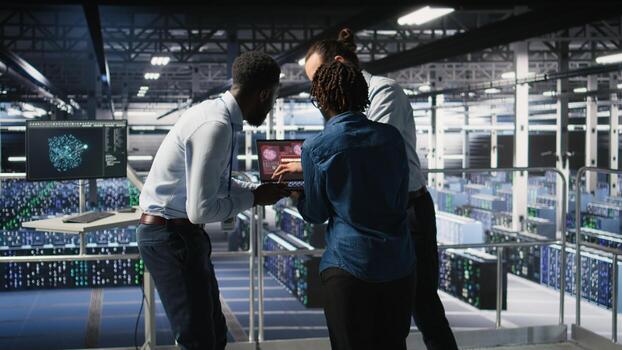 Worried workers trying to fix hacked infrastructure systems. Panicked engineers in data center react to ransomware warning on laptop screen, scrambling to launch emergency response protocol, photo