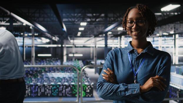 Portrait of smiling data center admin next to coworkers running diagnostics on equipment to identify errors. Happy woman next to IT experts working to prevent failure and minimize downtime, photo