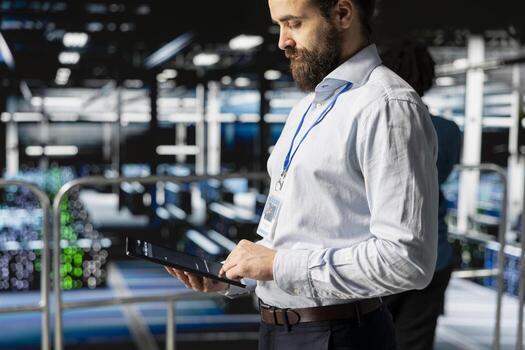 Technician holding tablet to review system diagnostics on server farm platform, doing machine learning automatization. Data center programmer doing maintenance with artificial intelligence. photo