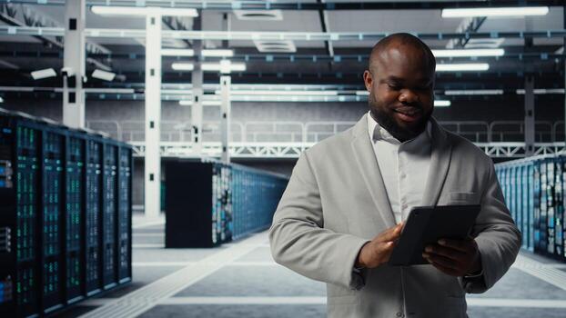 Server room worker troubleshooting server connectivity issues using software on tablet. Data center technician upgrading enterprise networks hardware using device, camera A photo