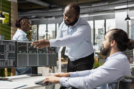 Manager and man with paraplegia in prop firm office executing trades using trading app on PC. Team leader and person with disability in wheelchair monitoring stock exchange data photo