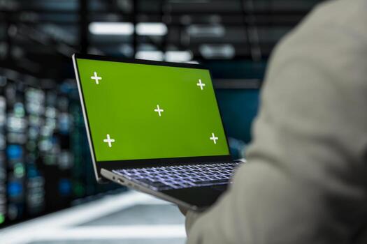 Close up of server farm software developer using mockup laptop to repair equipment storing datasets. IT specialist using green screen notebook to debug rackmounts doing computational operations photo