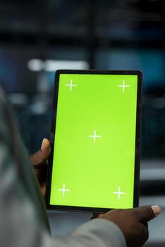 Close up of server farm software developer using mockup tablet to repair equipment storing datasets. Data center worker using green screen device to debug mainframes doing computational operations photo