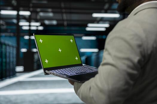 Close up of data center technician using green screen laptop, managing rigs energy consumption. IT specialist using mockup notebook used for monitoring processes in server room photo