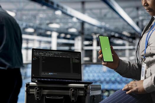 Close up of data center admin using green screen smartphone to relax while waiting for coding script to finish running. Server farm worker scrolls on chroma key phone, responding to texts during break photo