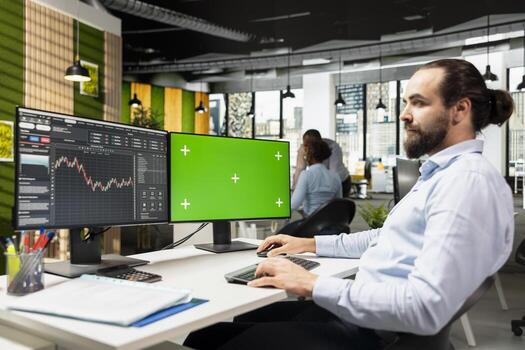 Day trader using software on green screen PC to capitalize on market fluctuations when buying and selling stocks. Prop firm office worker uses chroma key computer to identify profit opportunities photo
