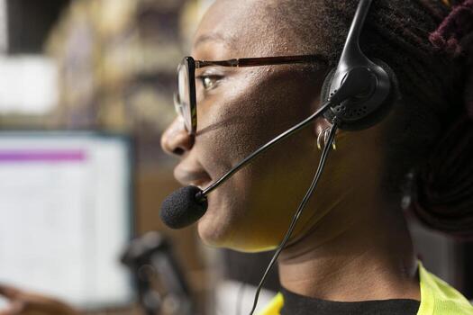 Close up of black woman answering calls from customers in a distribution hub, managing mix up problems and requests via customer support help line. Call center employee with headset. photo