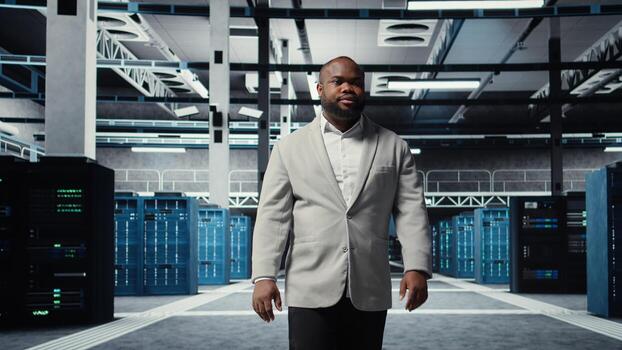 Smiling engineer walking in data center, checking hardware for system stability. Happy employee overseeing server farm, configuring infrastructure to optimize performance, camera A photo