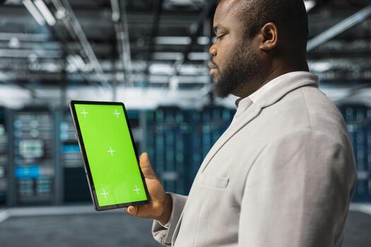 Close up of data center computer scientist using green screen tablet in data center, reviewing configurations. Server hub software developer using mockup device, scanning hardware logs for faults photo