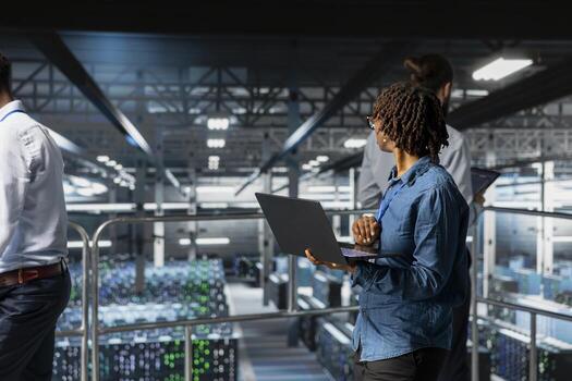 African american IT specialist ensuring server hub tech automation, reviewing AI LLM visualizations in data center. IT professional analyze neural network systems for infrastructure. photo