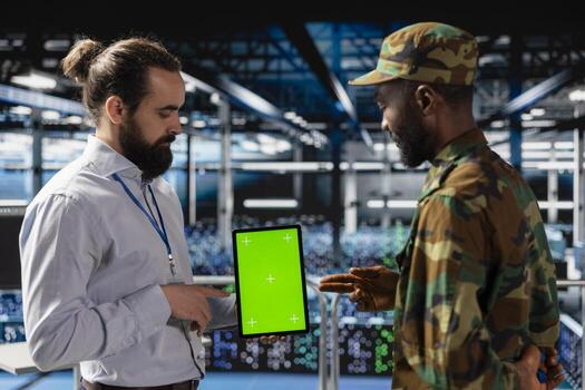 Diverse military base employees in data center use isolated mockup tablet to monitor defense systems via satellite surveillance. Army operators team ensuring government protection. photo