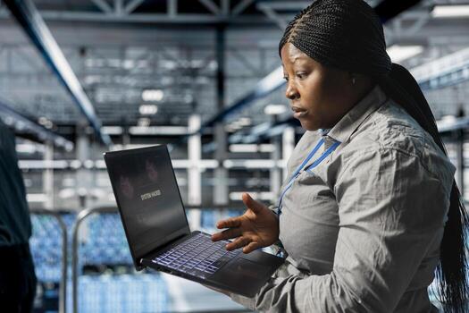Engineer in server room trying to minimize damage of hacking incident involving theft of sensitive data. Data center employee alarmed by computer virus triggered by security systems photo
