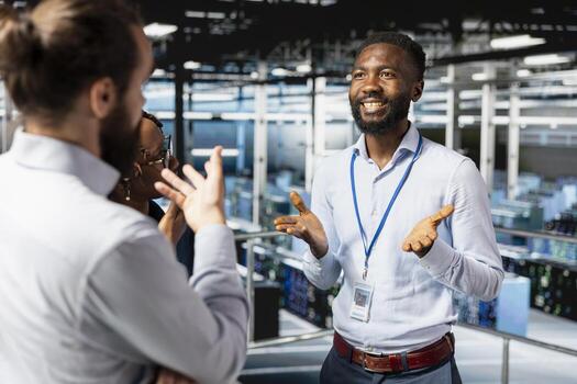 Smiling diverse engineering team reviewing performance dashboards with AI tools for server rigs. Server room workers overseeing machine learning algorithms on platform workstation. photo